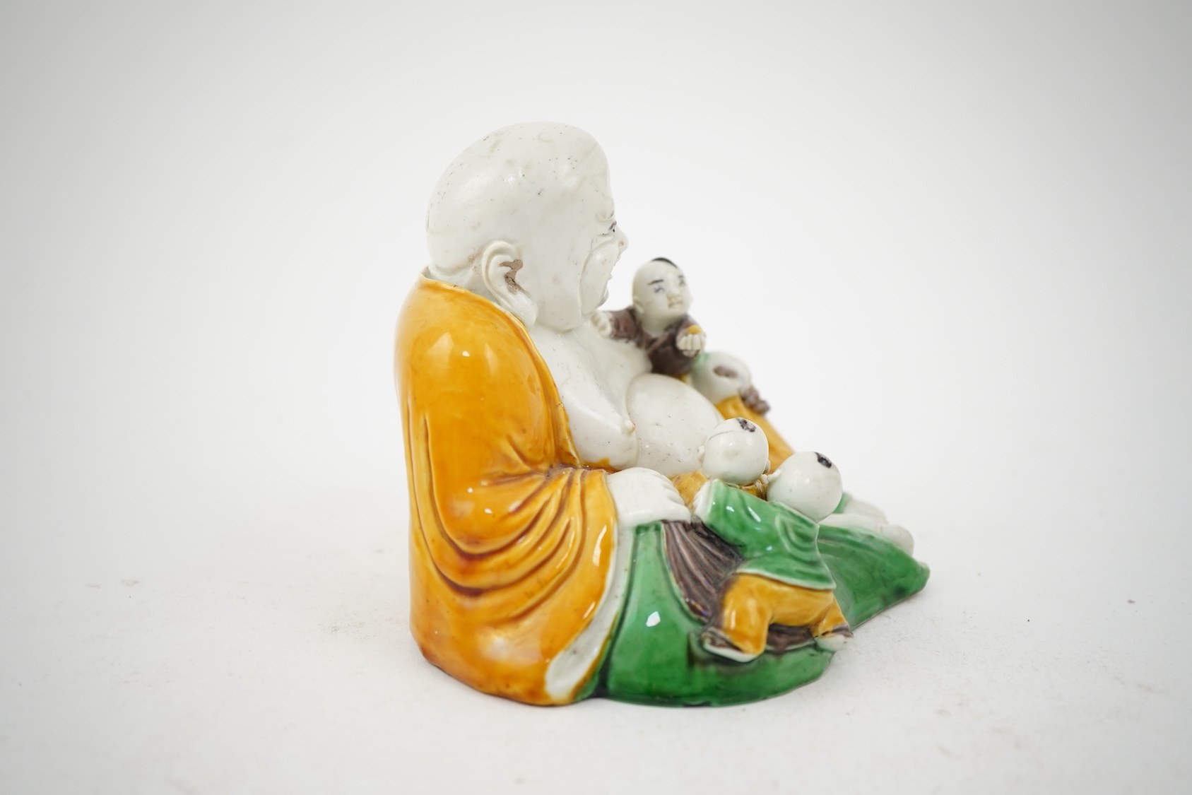 A Chinese sancai glazed biscuit group of Budai and three boys, 19th century